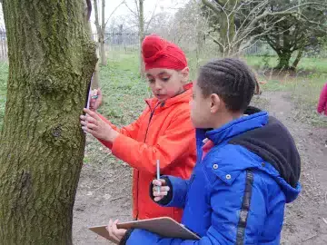 Two pupils take notes by a tree