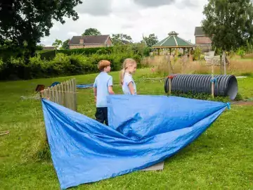 Two students hold a blue groundsheet