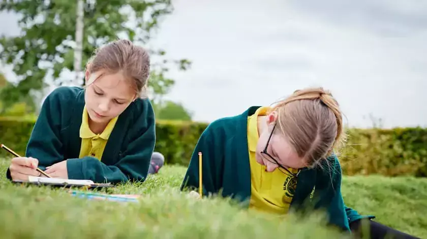 students writinngg on grass