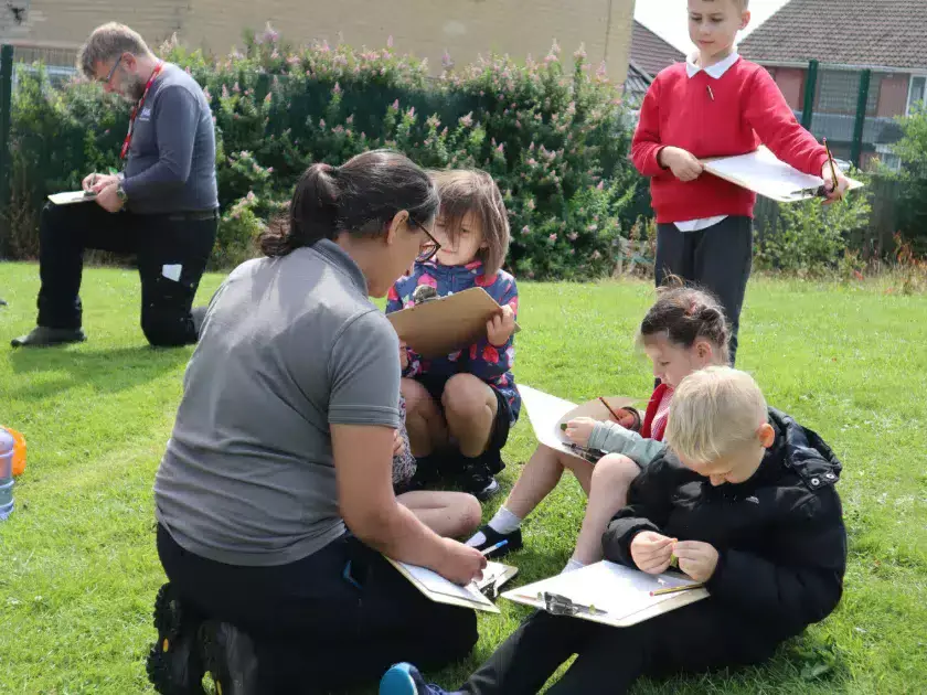 Nature park team members with pupils outside looking at clipboards