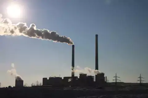 Factory with tall smoking chimney stacks